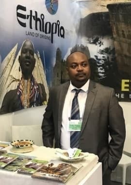 Yama Ethiopia Tours representative in a suit at an Ethiopia tourism exhibition booth