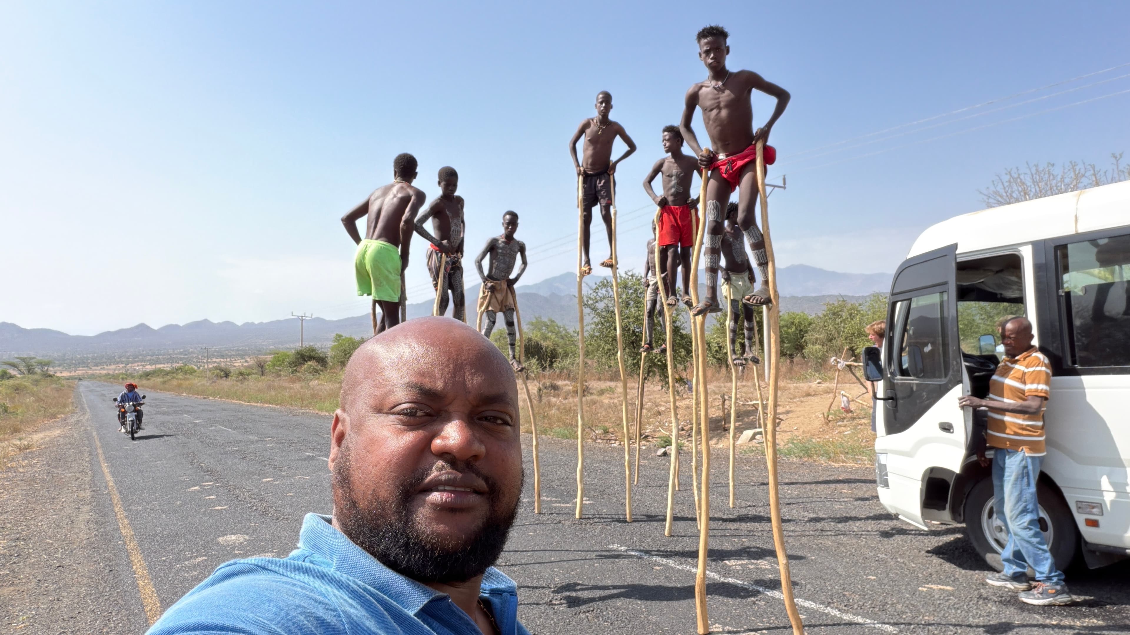 A group of young Banna men balanced on tall wooden stilts along a roadside in the Omo Valley, Ethiopia