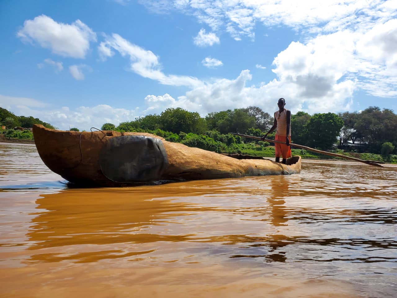 Local tribal boatman paddling a traditional carved wooden dugout canoe across the Omo River in Southern Ethiopia