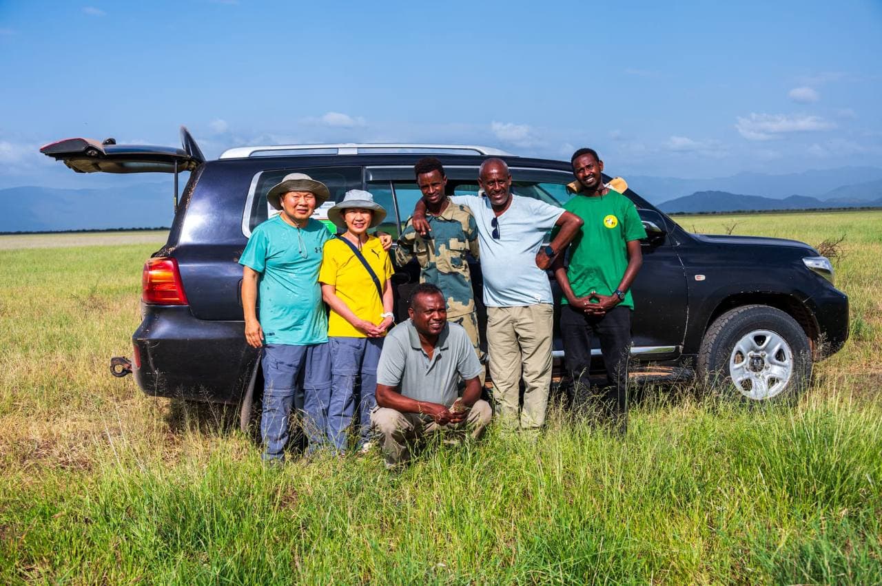Tour group and guides posing with their safari vehicle in the Omo Valley
