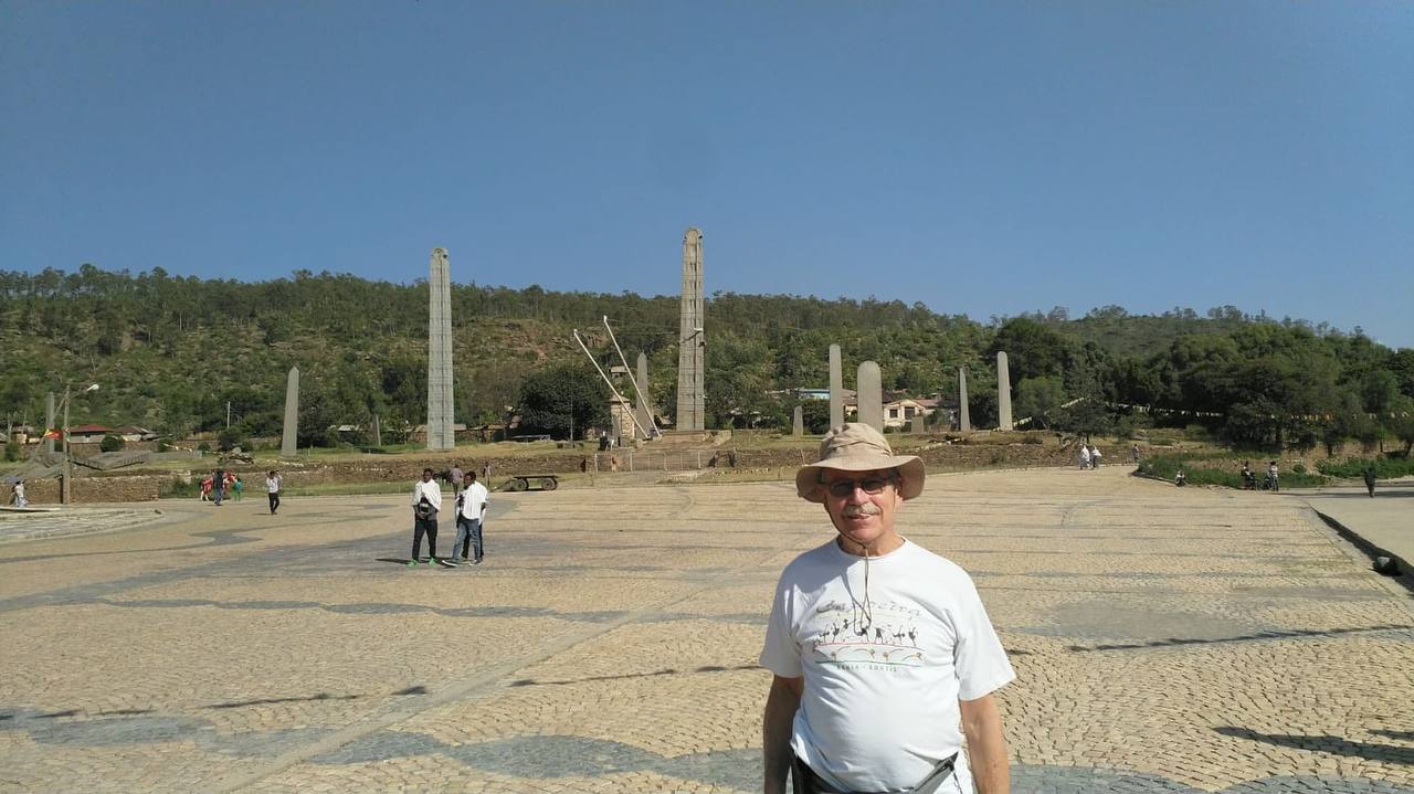 Visitors walking across the cobbled plaza in front of the towering ancient granite obelisks of the Aksum Stelae Field, Tigray, Ethiopia