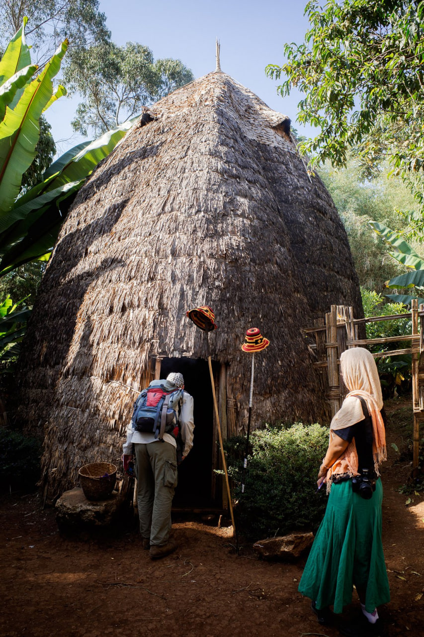 Travelers entering a traditional Dorze beehive-shaped bamboo hut in southern Ethiopia