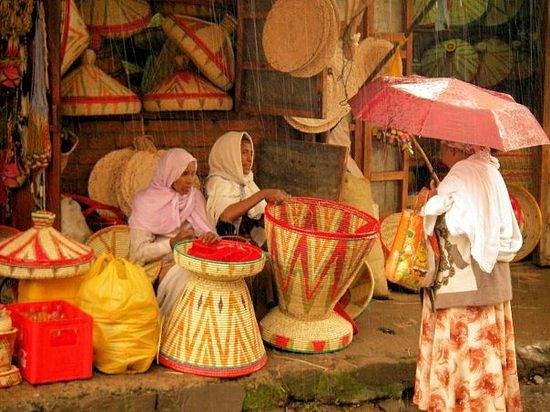 Vendors selling traditional woven baskets at a market stall in the rain, Ethiopia