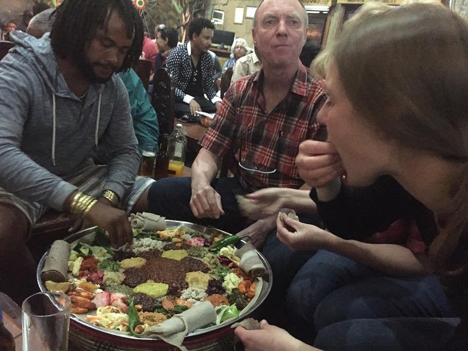 Friends sharing a traditional Ethiopian injera platter at a local restaurant