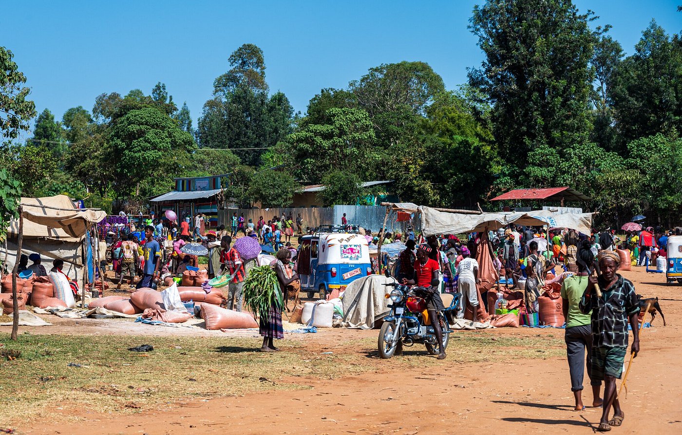 Bustling open-air market day with vendors and motorbikes in rural Ethiopia