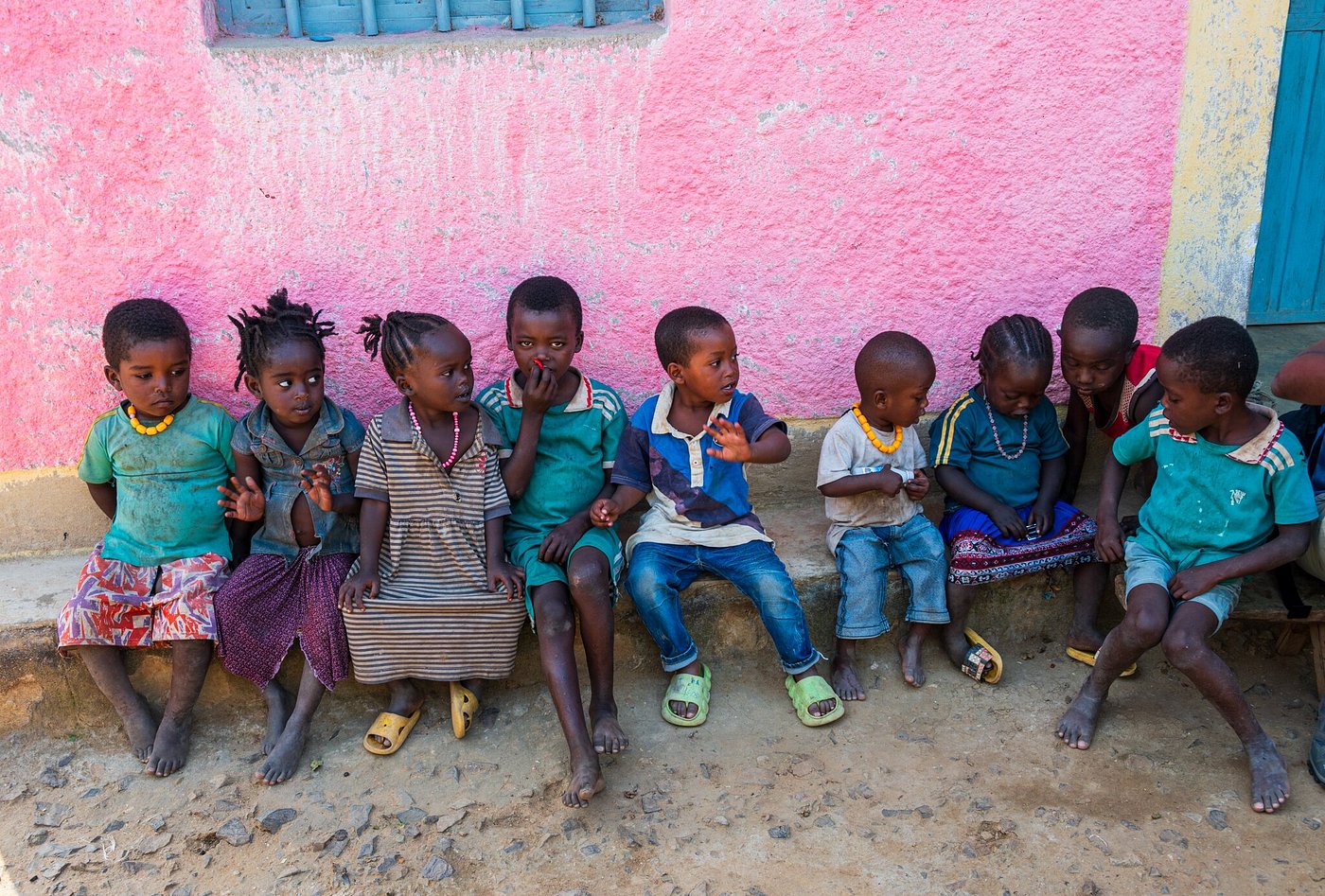 Group of local children sitting together against a colorful painted wall in Ethiopia