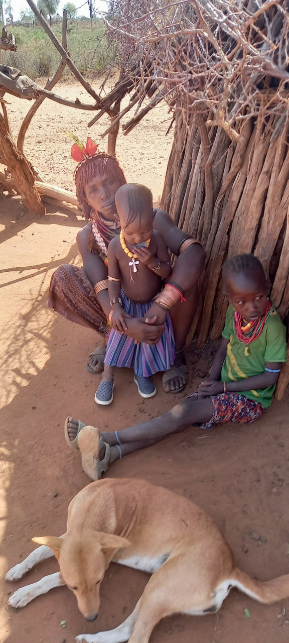 Hamar mother with children resting beside a traditional hut, Omo Valley