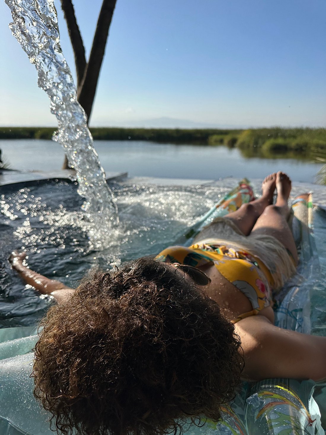 Traveler relaxing on a float in a natural hot spring pool overlooking a lake