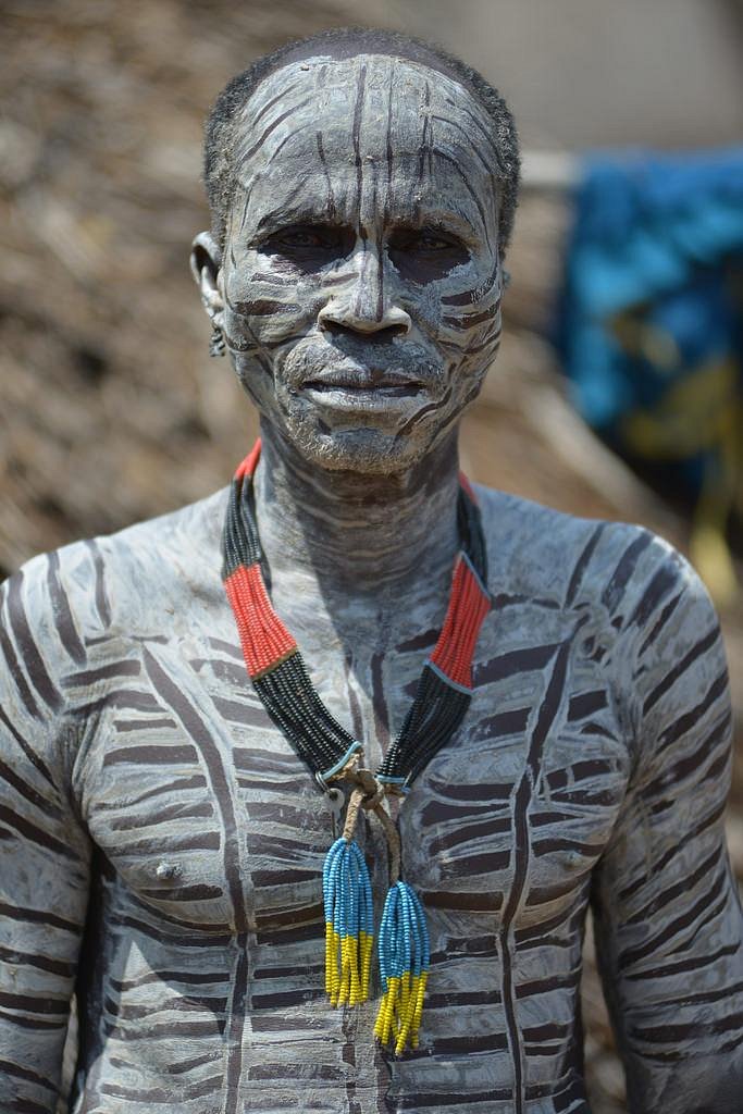 Omo Valley man with traditional gray body paint and beaded necklace, Ethiopia