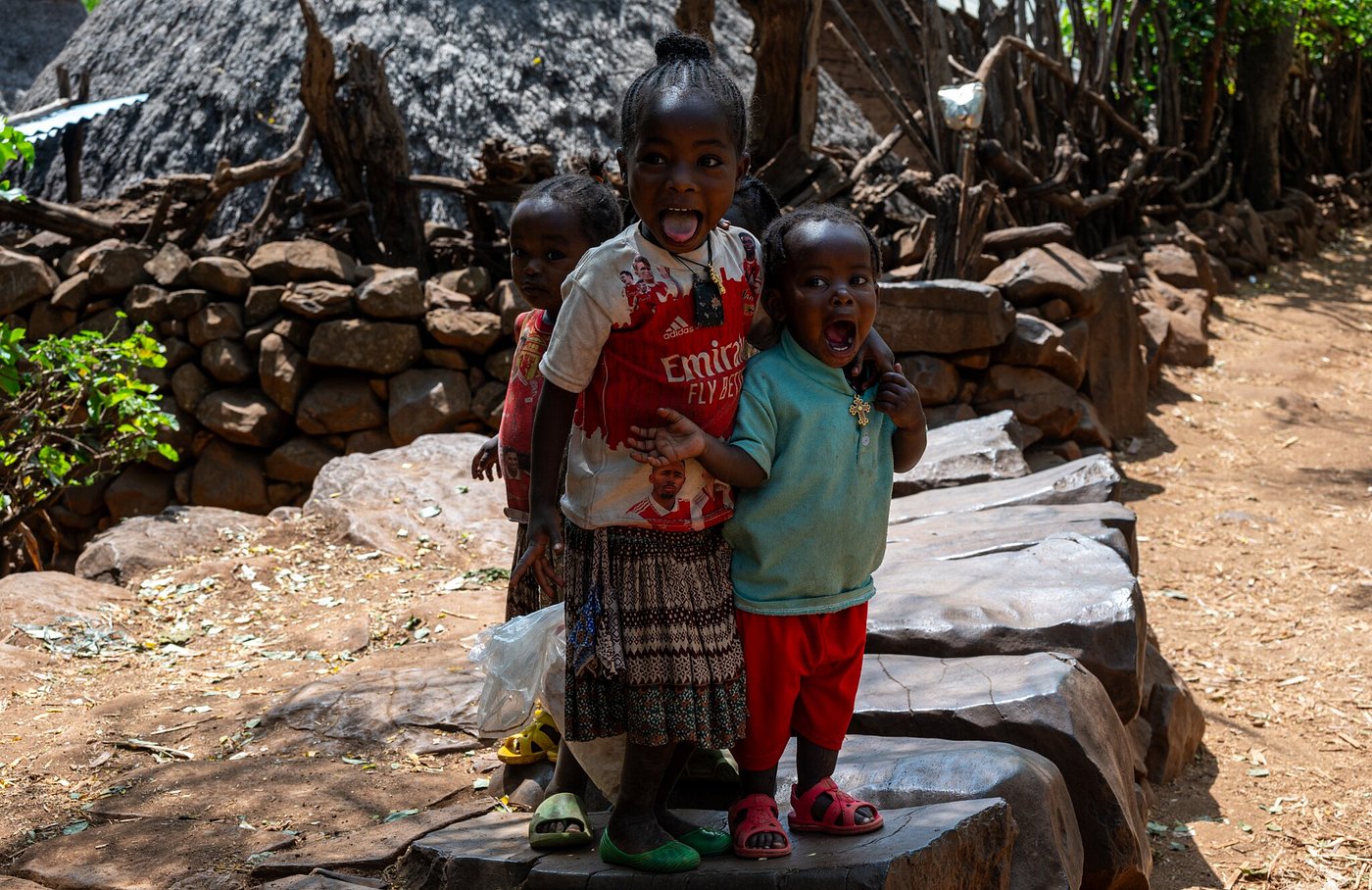 Smiling children posing playfully in a traditional village in southern Ethiopia