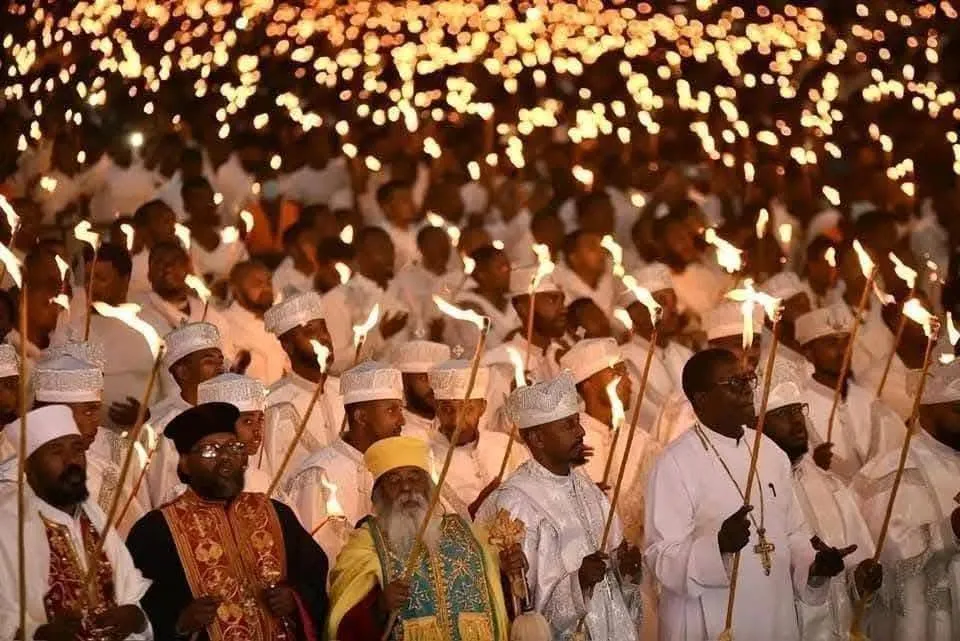 Silhouette of an Ethiopian Orthodox priest holding a cross before the blazing demera bonfire during Meskel Festival