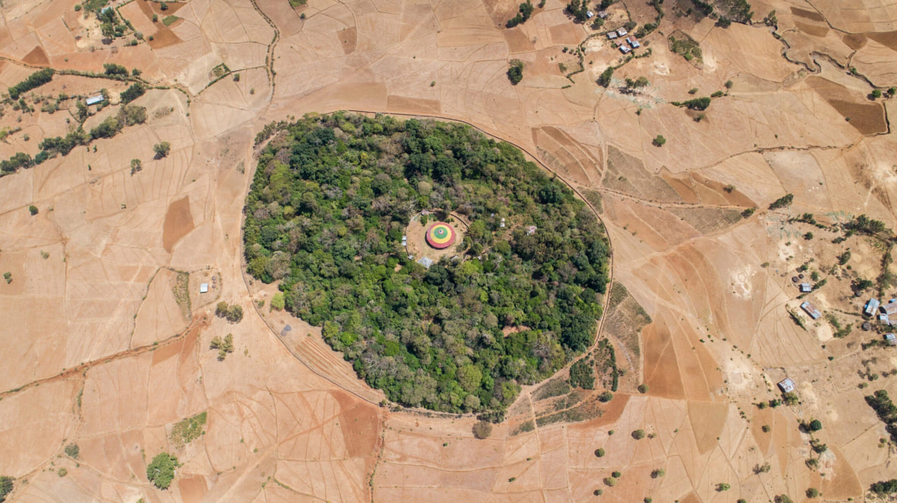 Aerial view of a circular sacred forest surrounding a rural Ethiopian church