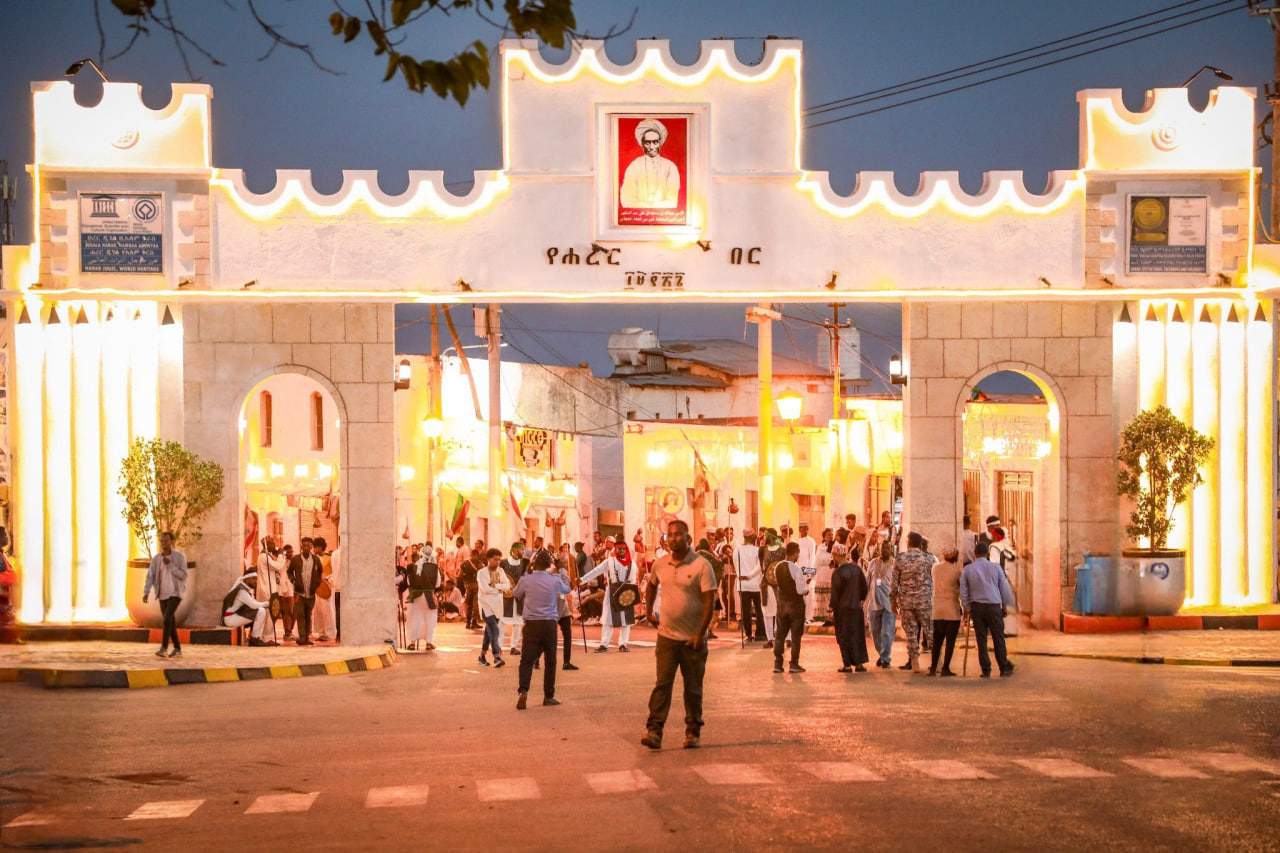 Illuminated Harar Jugol gate at night with crowds gathered for a festival